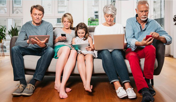 A family of five sitting on a couch using their digital devices