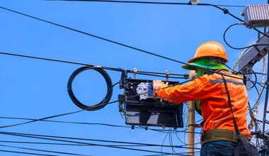 A man wearing a hard hat working on a telephone pole
