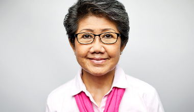 A smiling woman wearing a scarf and glasses.